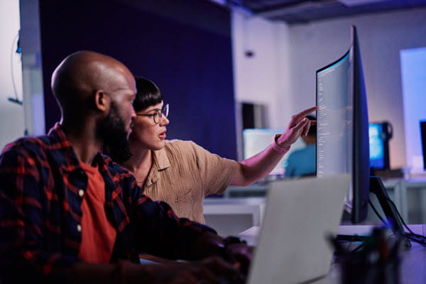 Two colleagues looking at lines of code together.