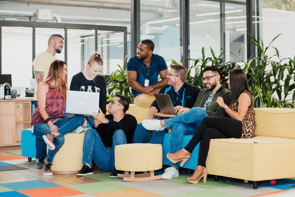 A large team meeting and talking around couches and chairs