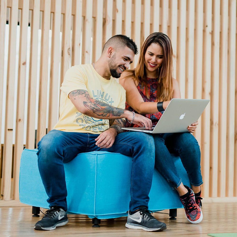 A man and woman sitting looking at a laptop. 