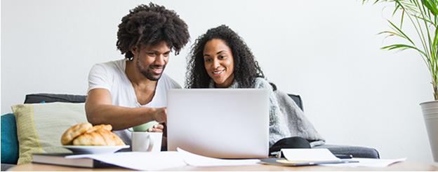 A man and woman working on a laptop while having breakfast