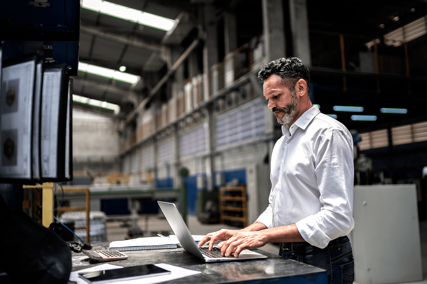 A man working on a laptop in a warehouse. 