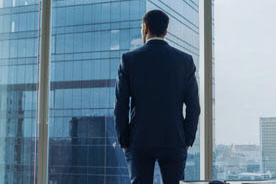 Business man in suit looking out of office window.
