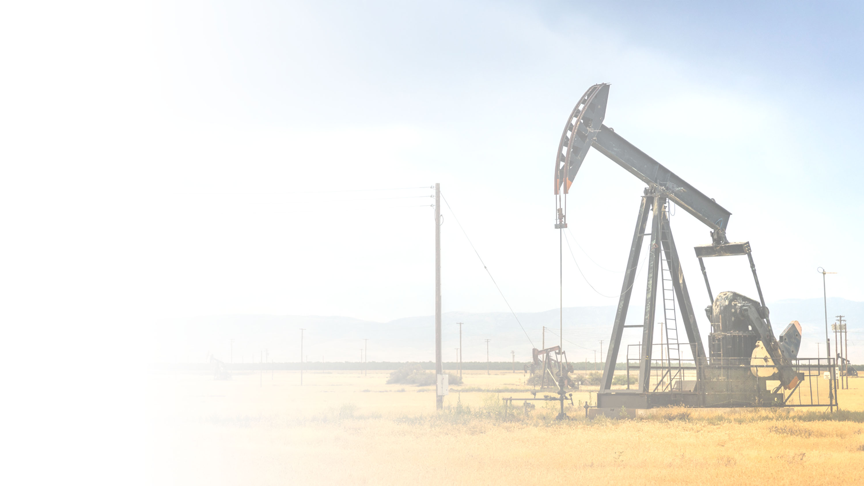 An oil jack pump in a field, gradient.