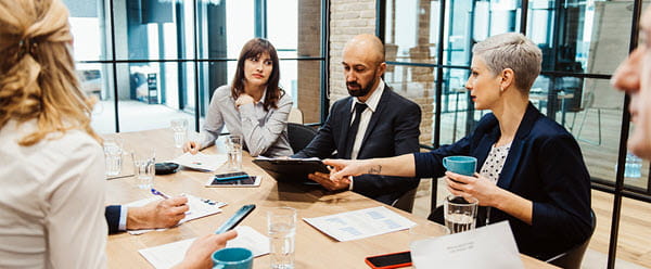 2 men and 2 women meeting in a glass meeting room at work