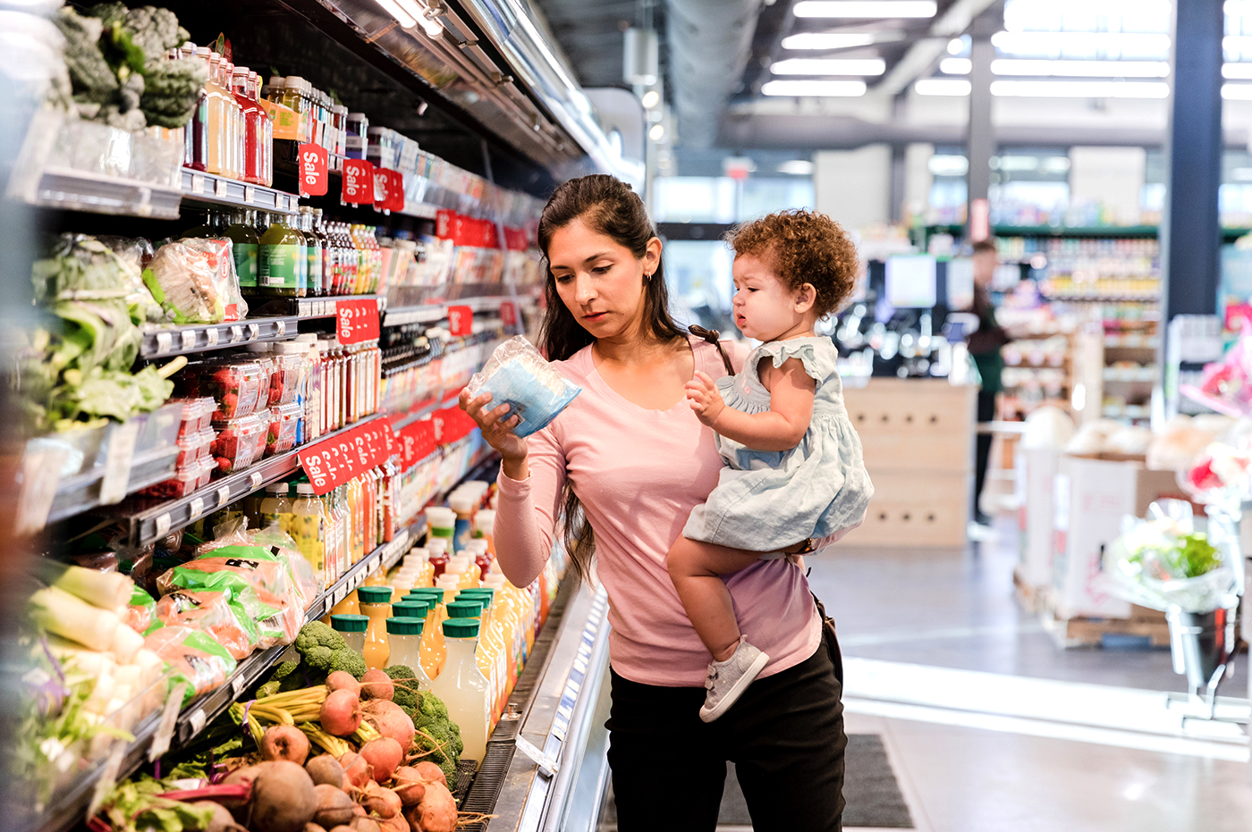 Woman holding child examining produce at the grocery store