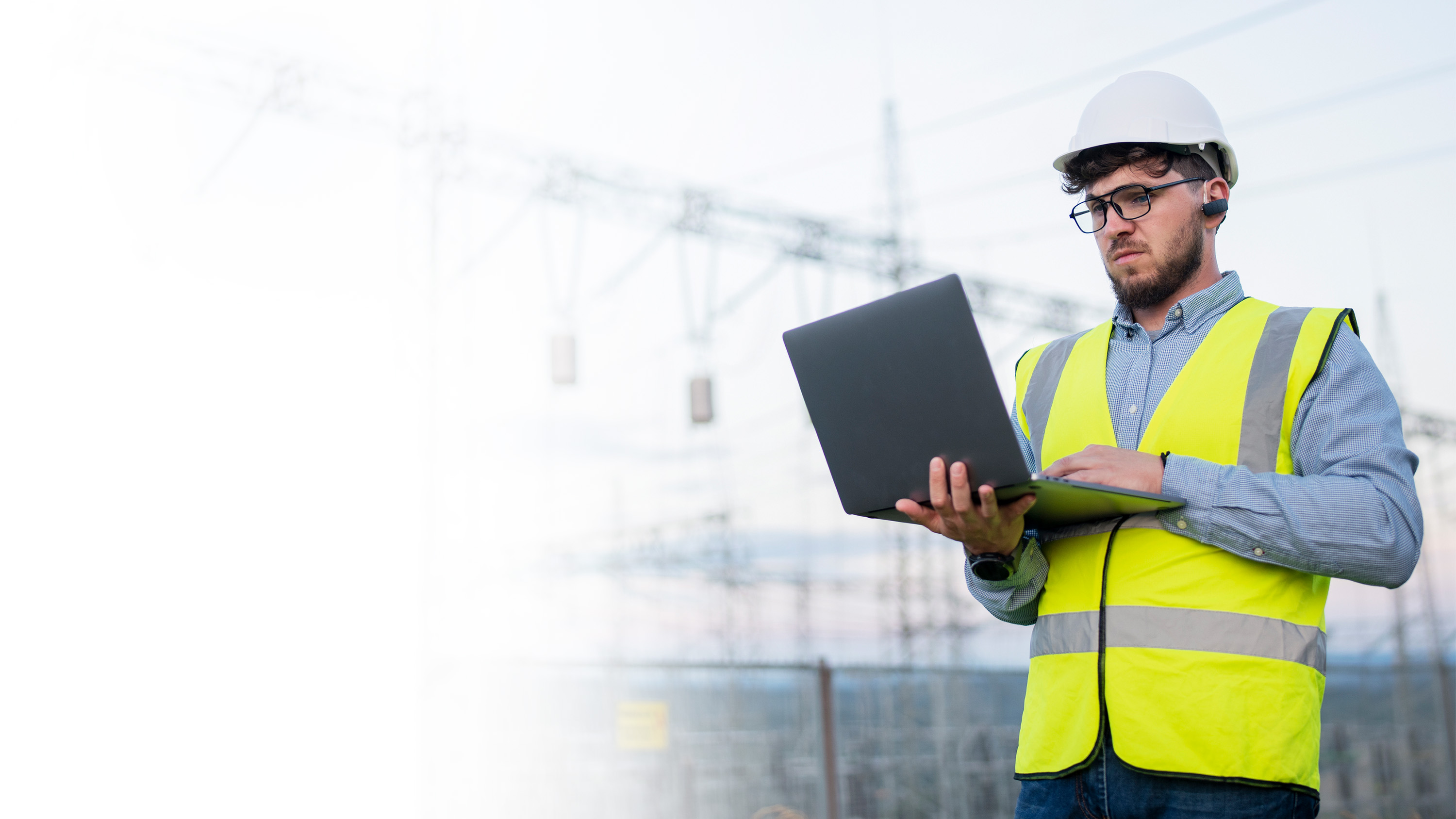 A man in a hardhat and vest on a laptop in an energy field, gradient.