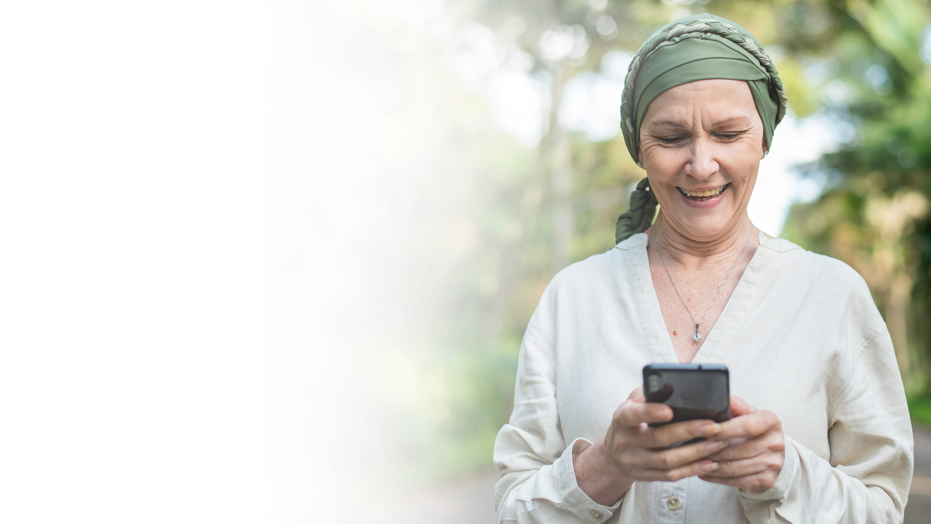 A woman in a headscarf looking on a smartphone, gradient.