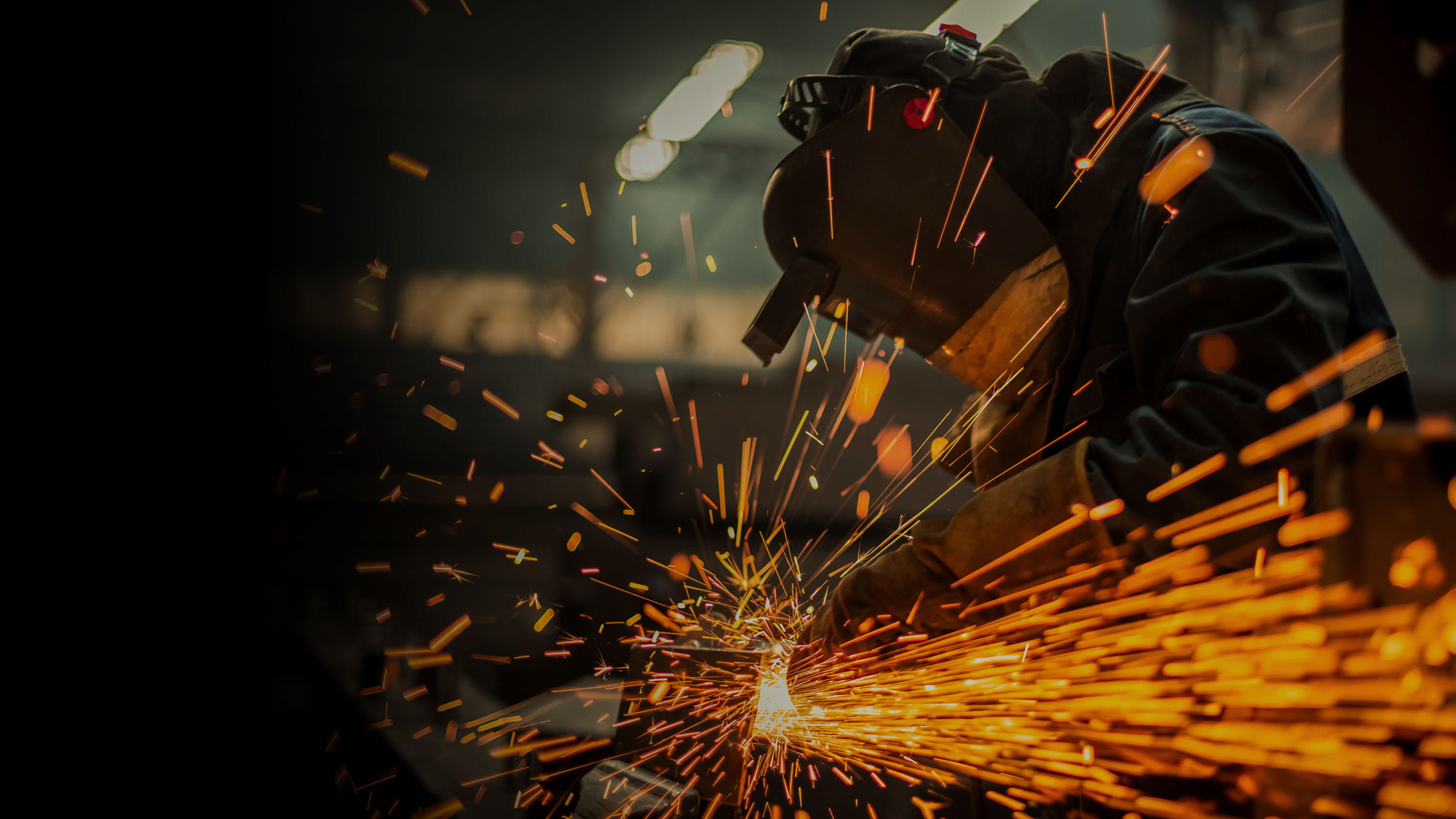 A person in protective gear welding metals, gradient.