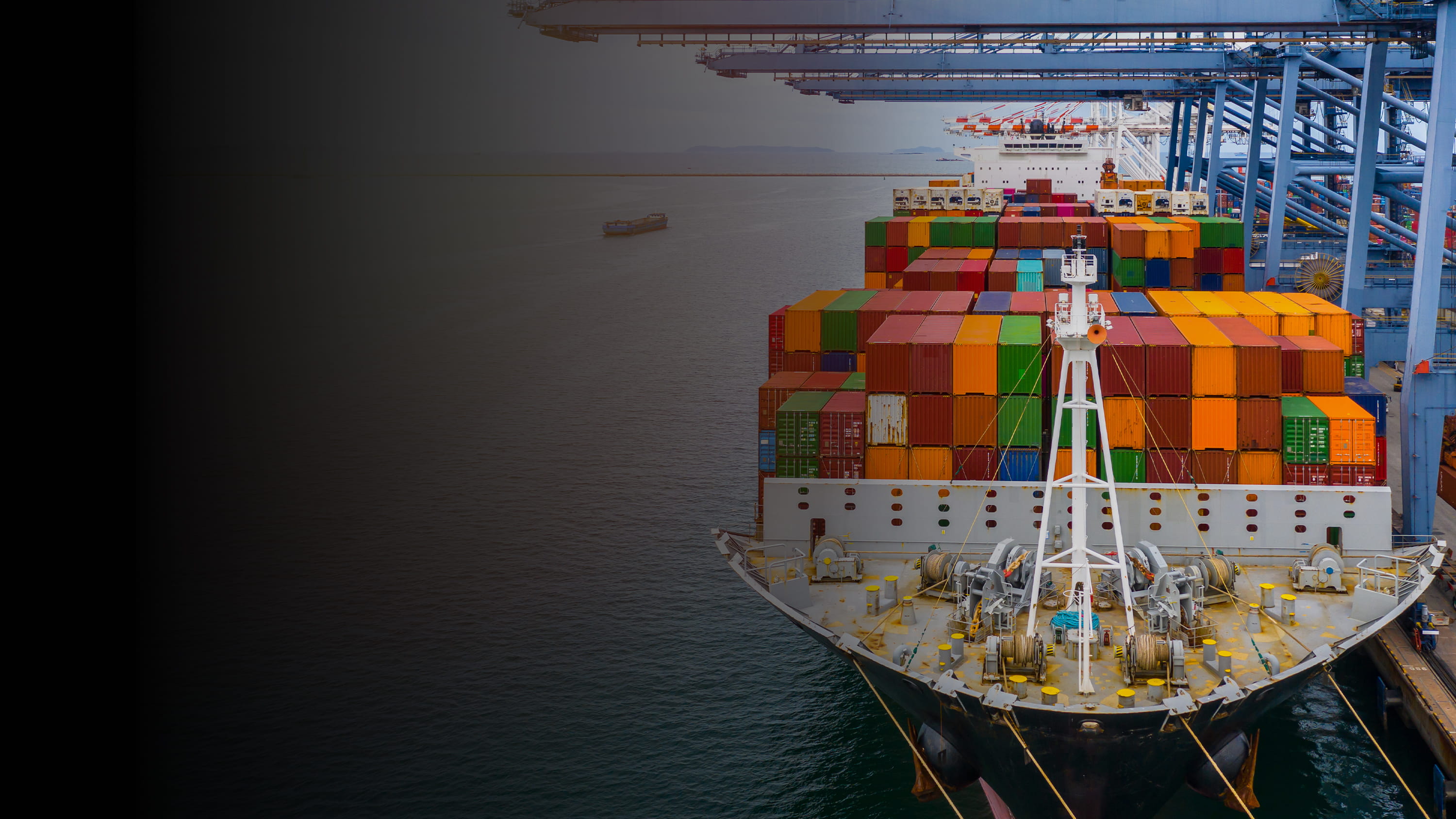 Gradient image of a cargo ship full of shipping containers at port.