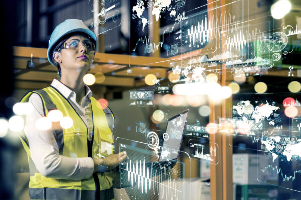 A woman at a manufacturing plant working with a computer and using AI.