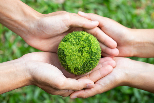  Two pairs of hands holding a green earth.