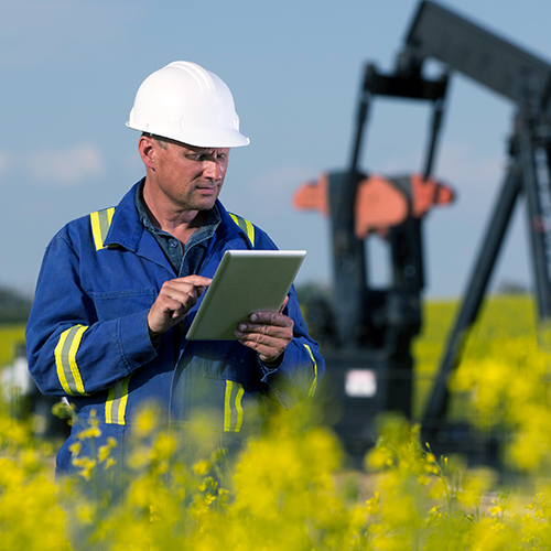 An oil worker using a tablet at a drilling site, tile card.