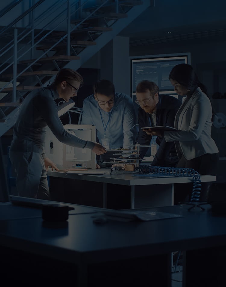 A group of people in a lab standing around a table working on something 