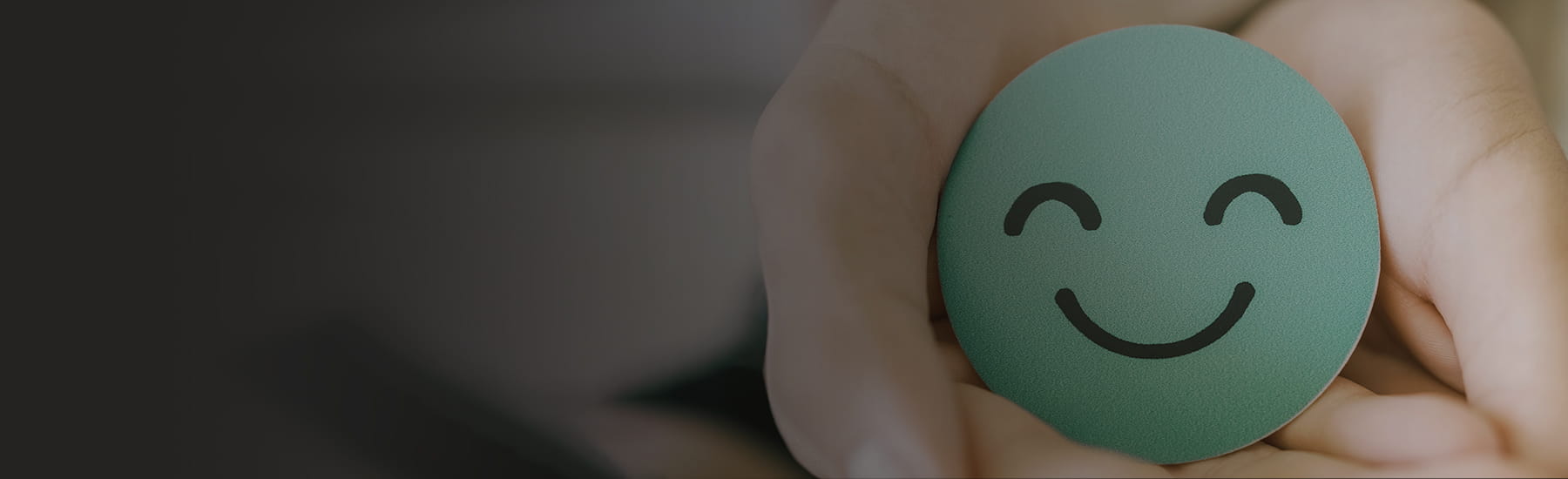 A hand holding a blue smiley face