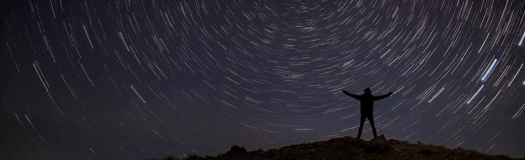 A man standing and facing a starry night sky