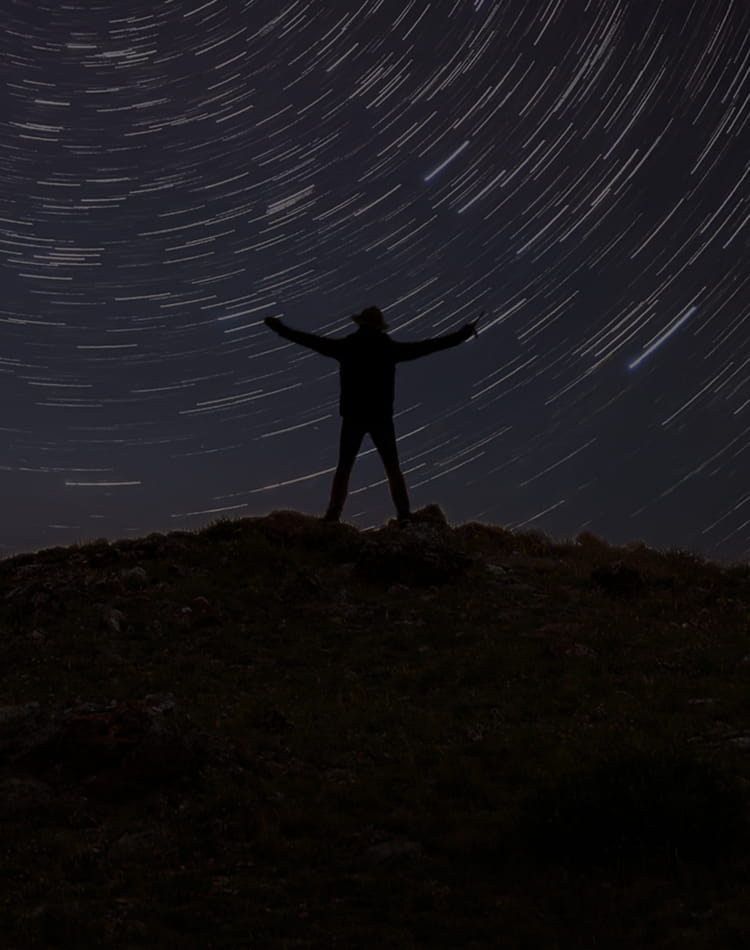 A man standing and facing a starry night sky