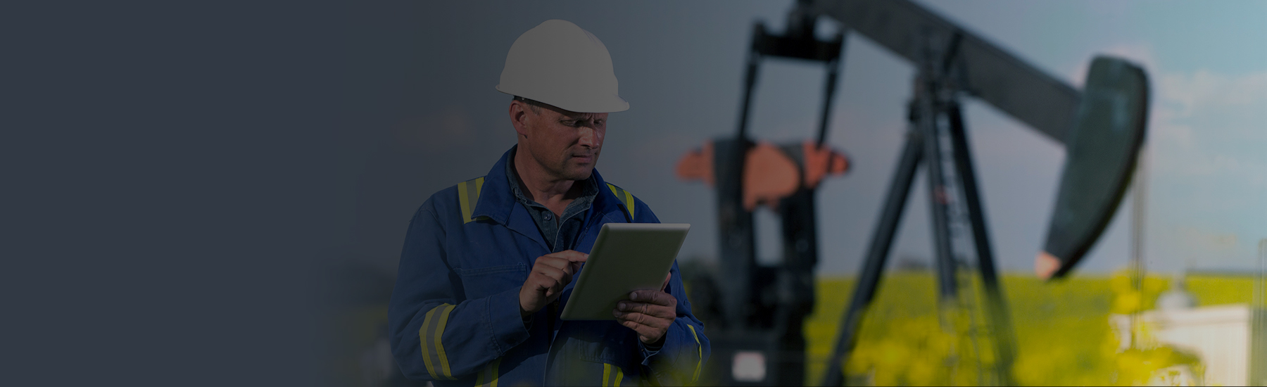 An oil worker using a tablet at a drilling site, desktop hero.