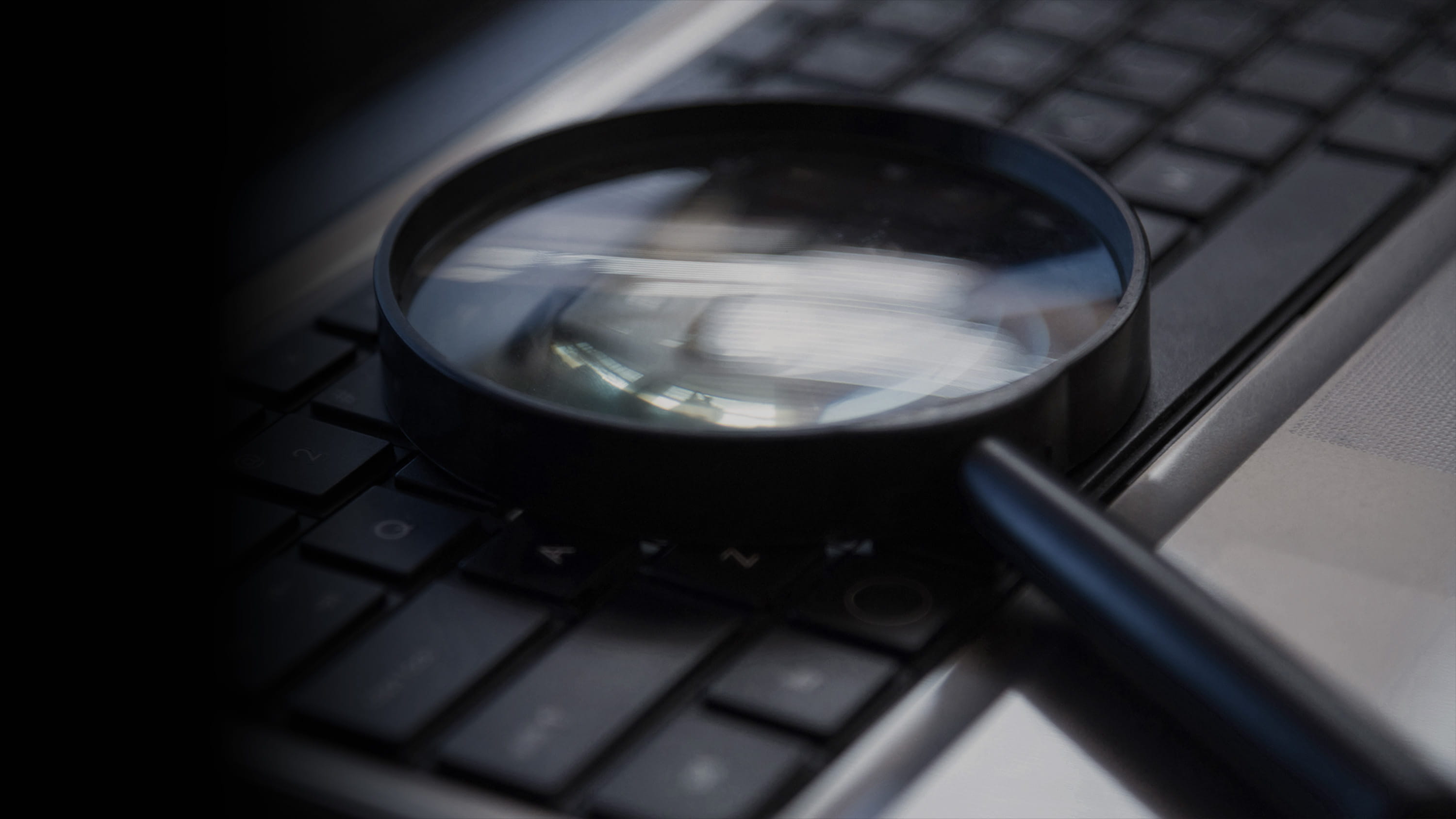 A magnifying glass sitting on top of a computer keyboard.