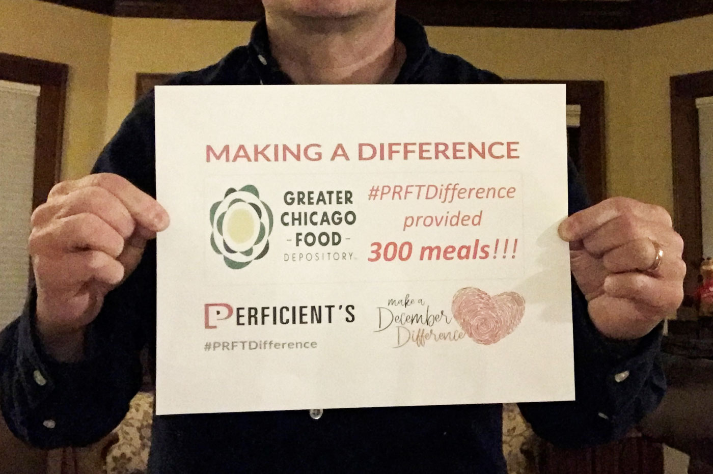 Colleague holding a December Difference Sign with grand total donated to Greater Chicago Food Depository.