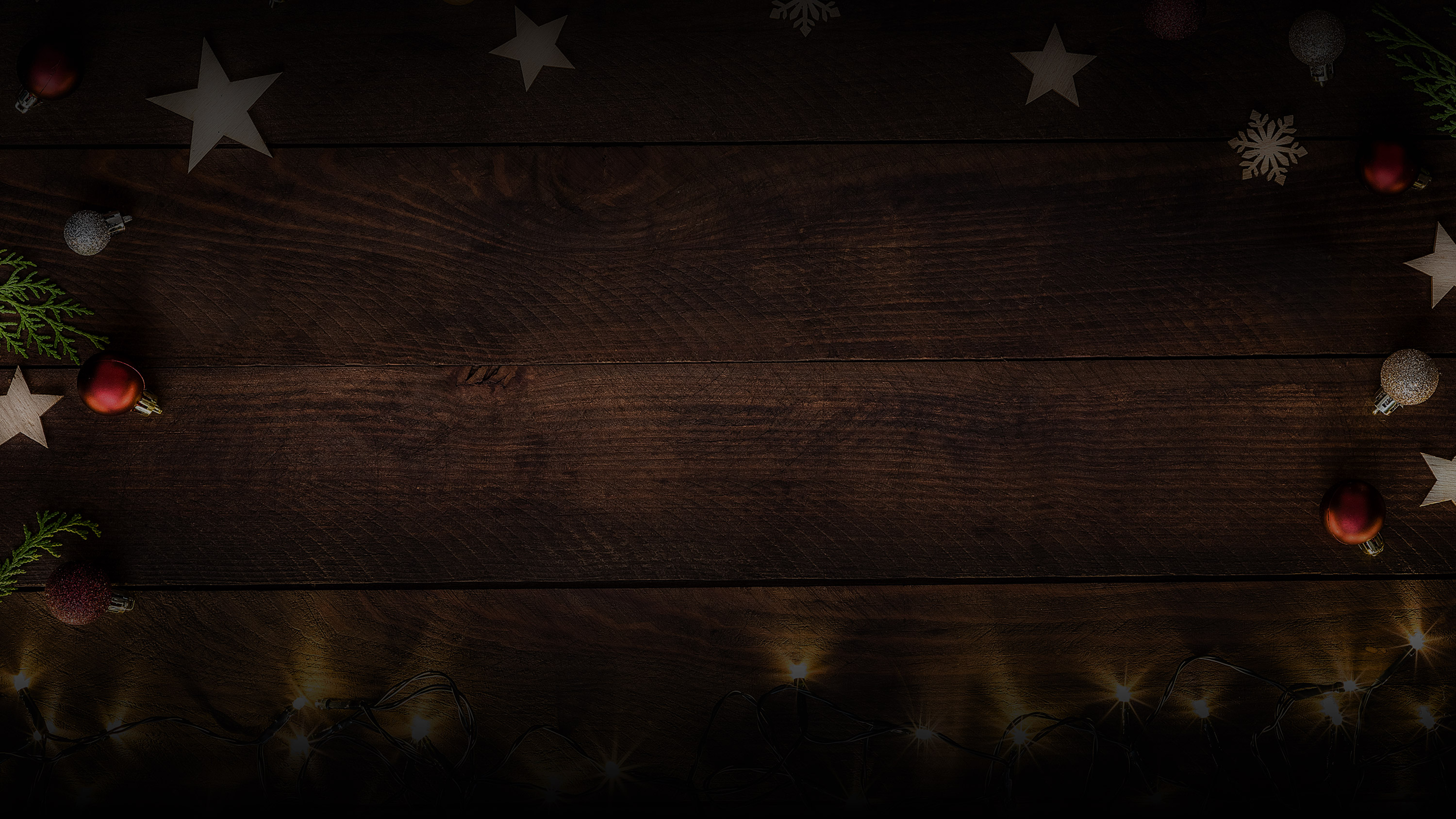 Background image of wooden surface with tree ornaments and stars framing it.