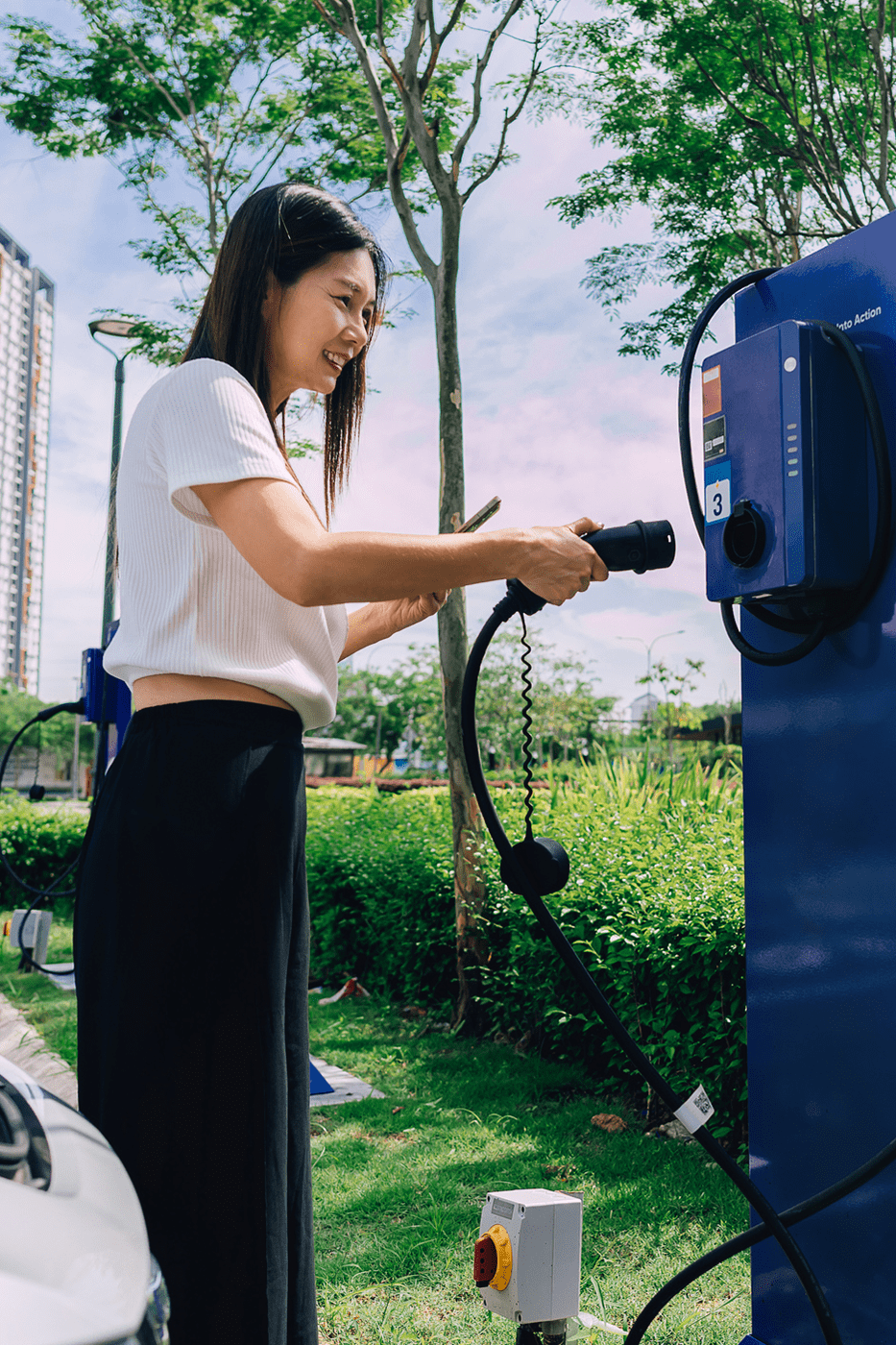 A woman plugging the charger back into the electric vehicle charging port