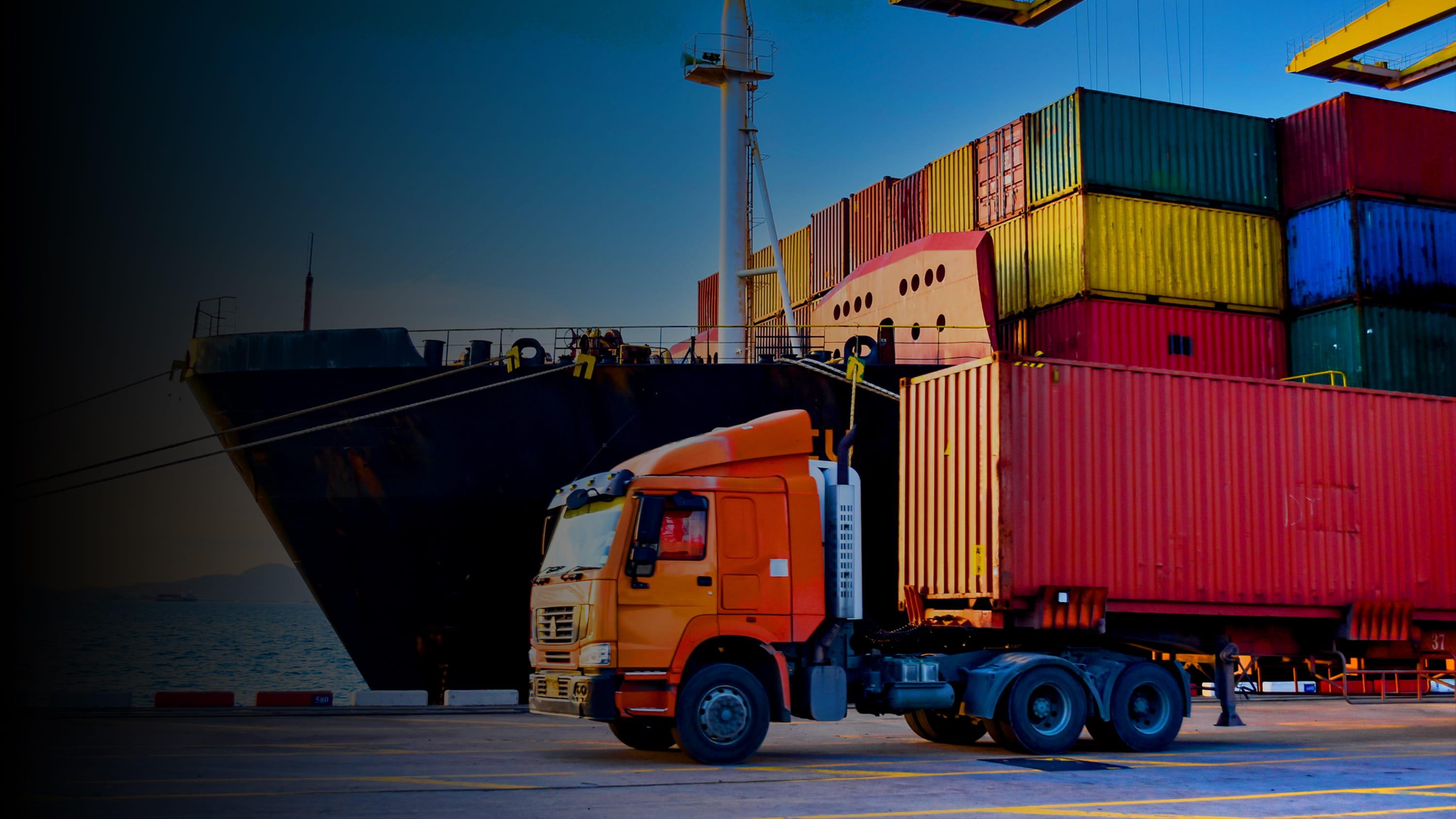 Freight boxes with a loading truck in front of them on a ship dock 