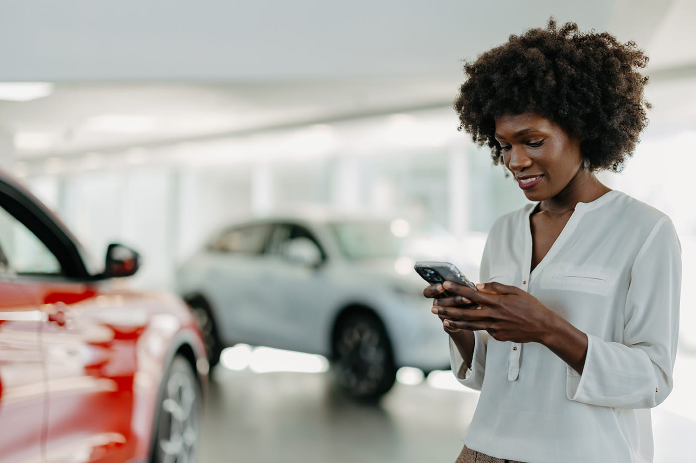 Person looking at phone in car showroom