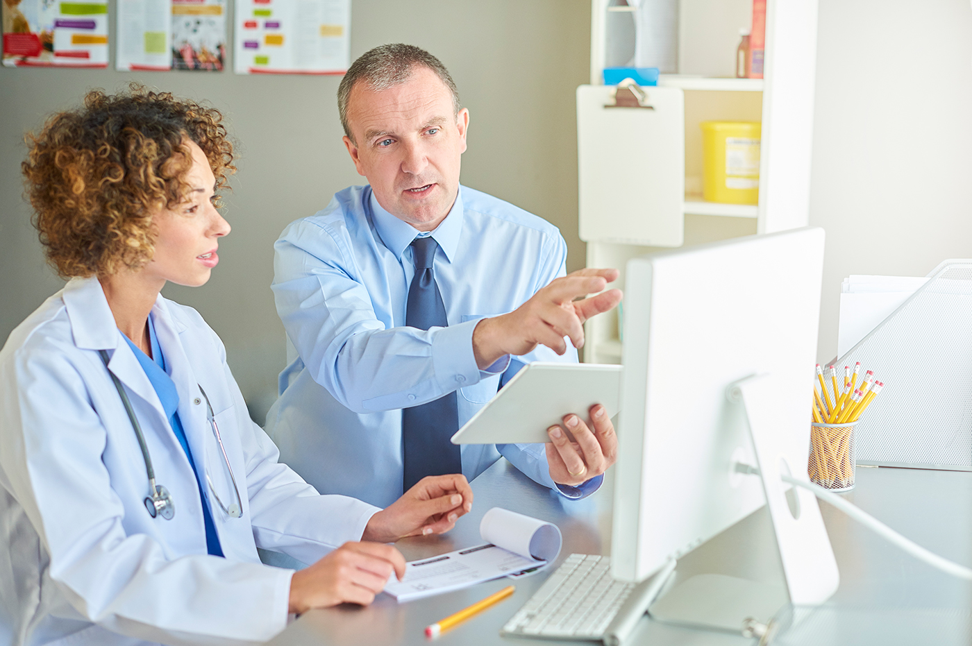 a female and male doctor in a healthcare office pointing at a computer screen