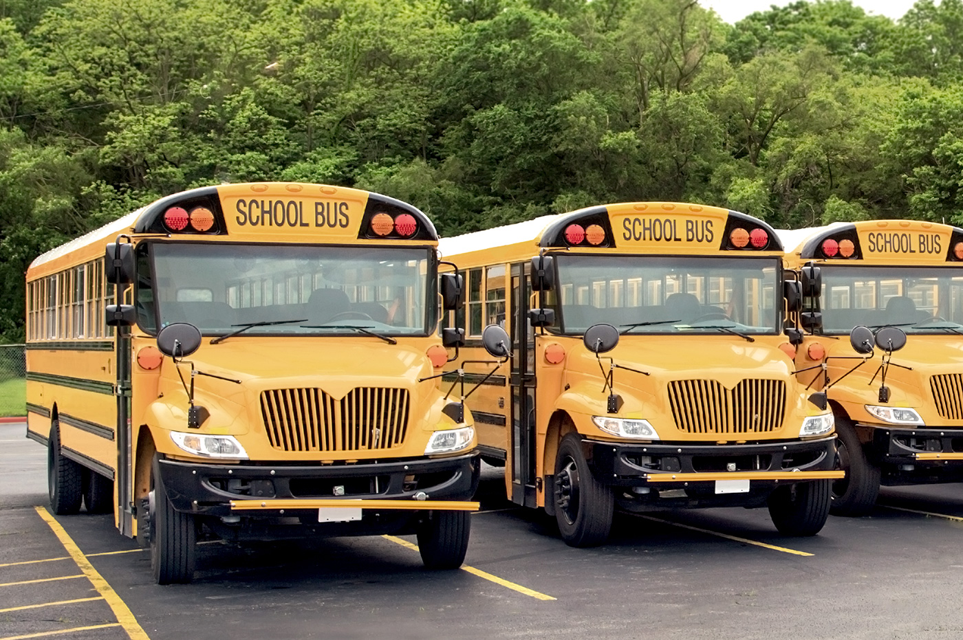 Three schoolbuses parked side by side in a parking lot.