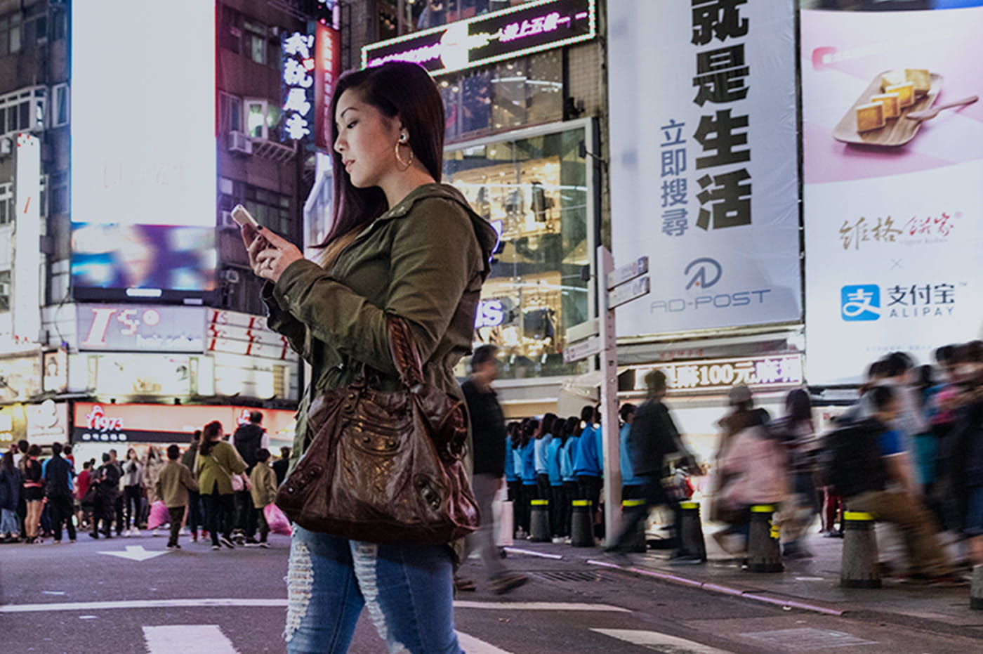 A young woman on her cellphone walking on a street in Asia.