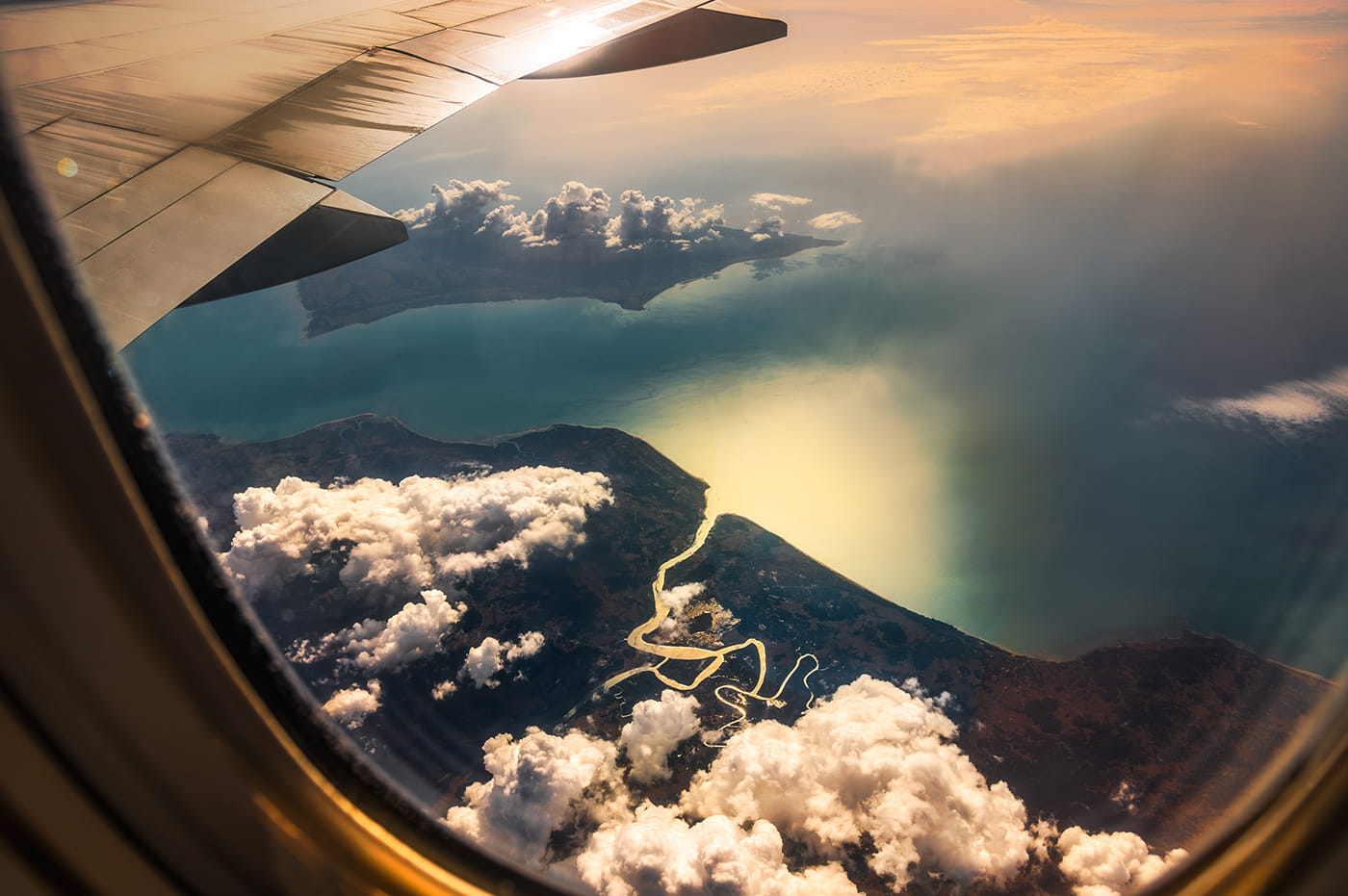 View from airplane window looking at the ground and coast below.