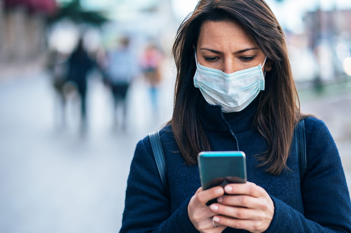 Woman in a facemask looking at her cellphone.