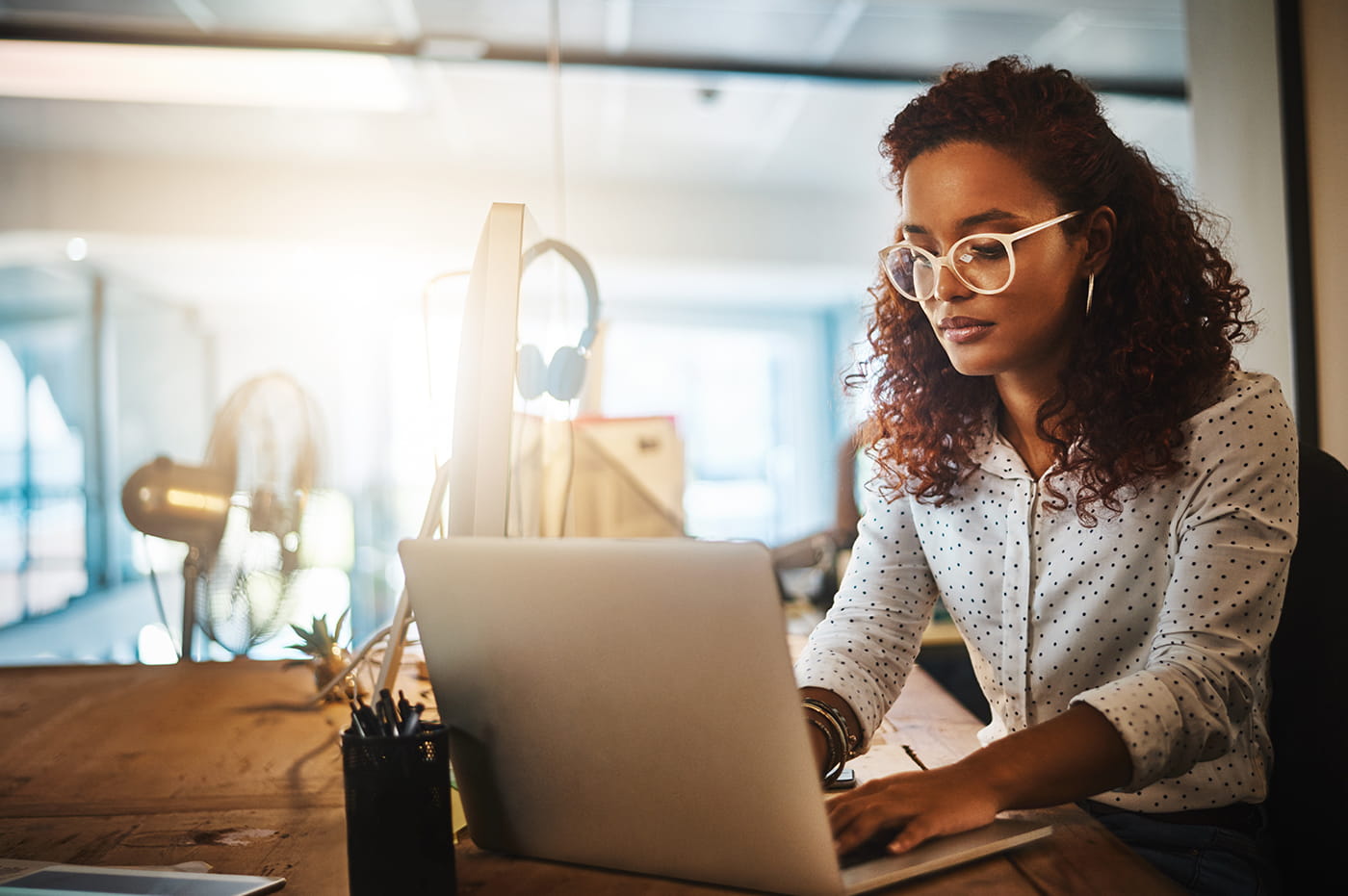 Young woman wearing glasses working on a laptop.