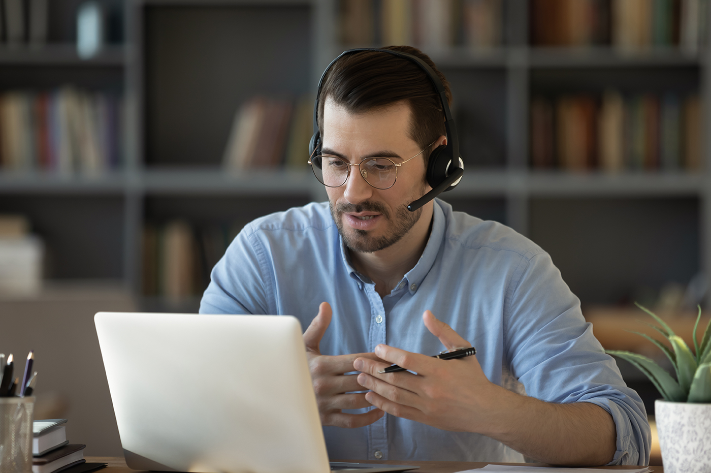 Man talking on a headset and working on laptop.