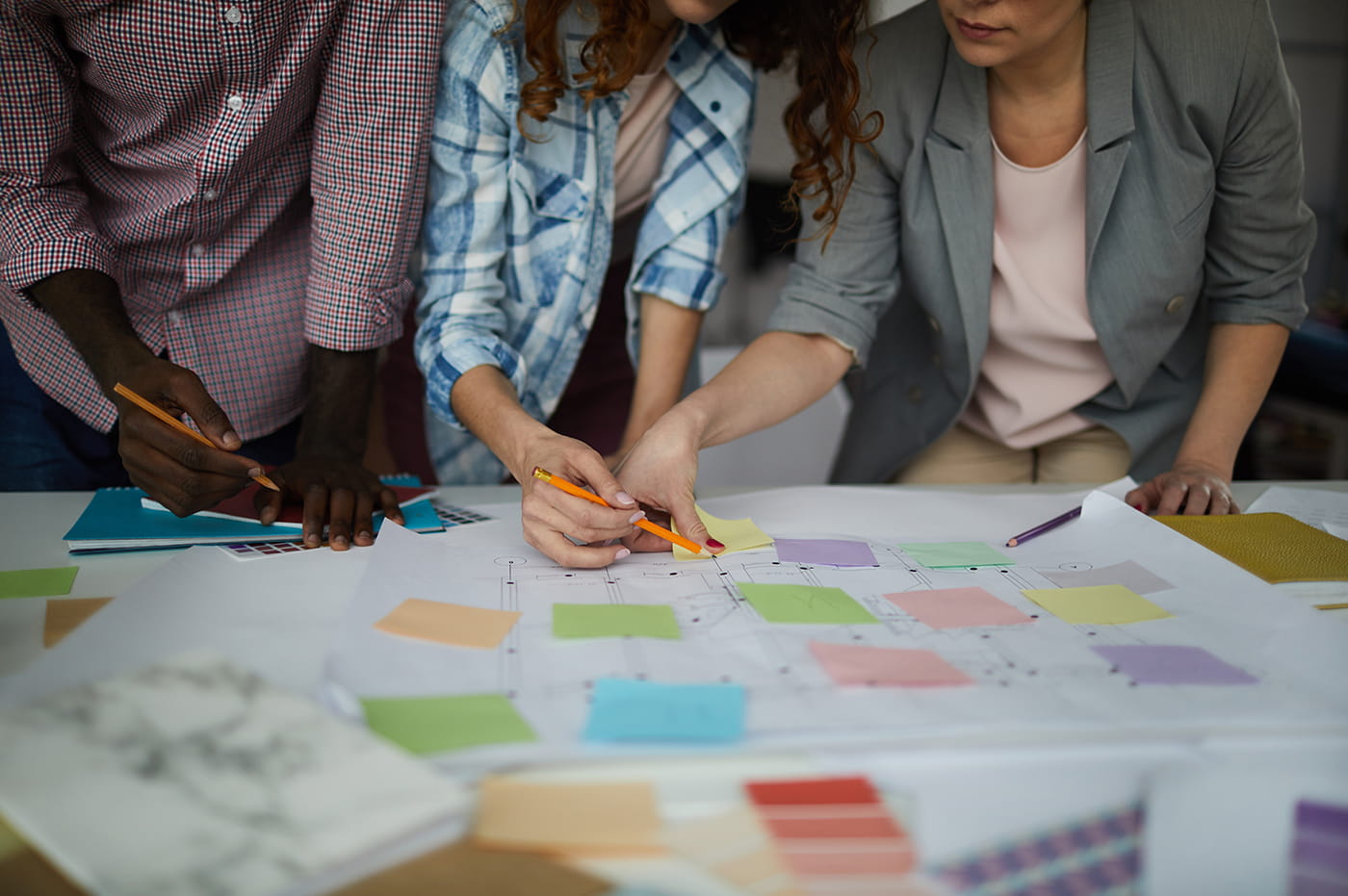 Three people discussing and working on a design board.