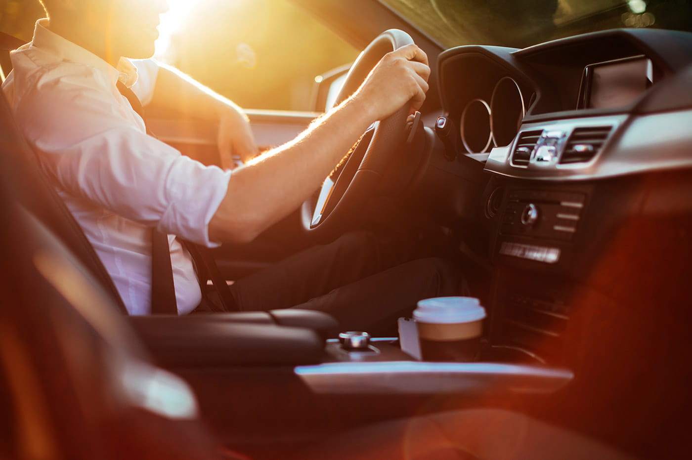 Man driving a car at sunset.