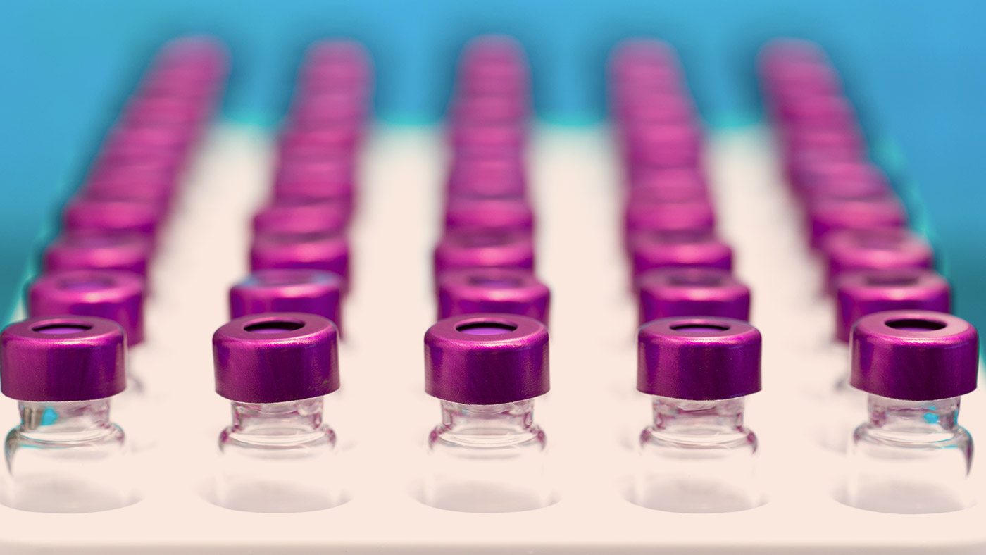 Tray of medicine vials with purple lids.
