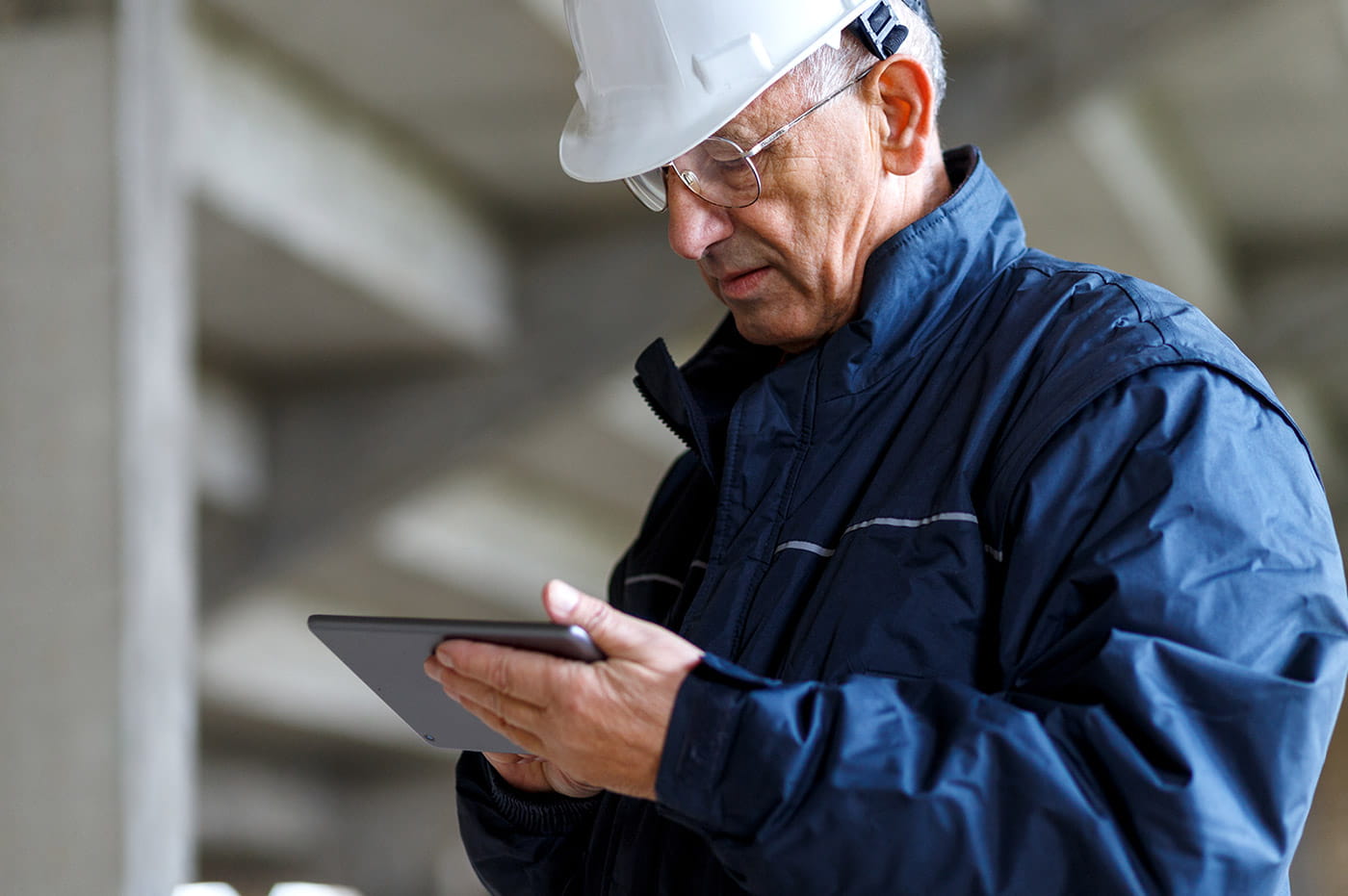 Older man in construction helmet working on an iPad.