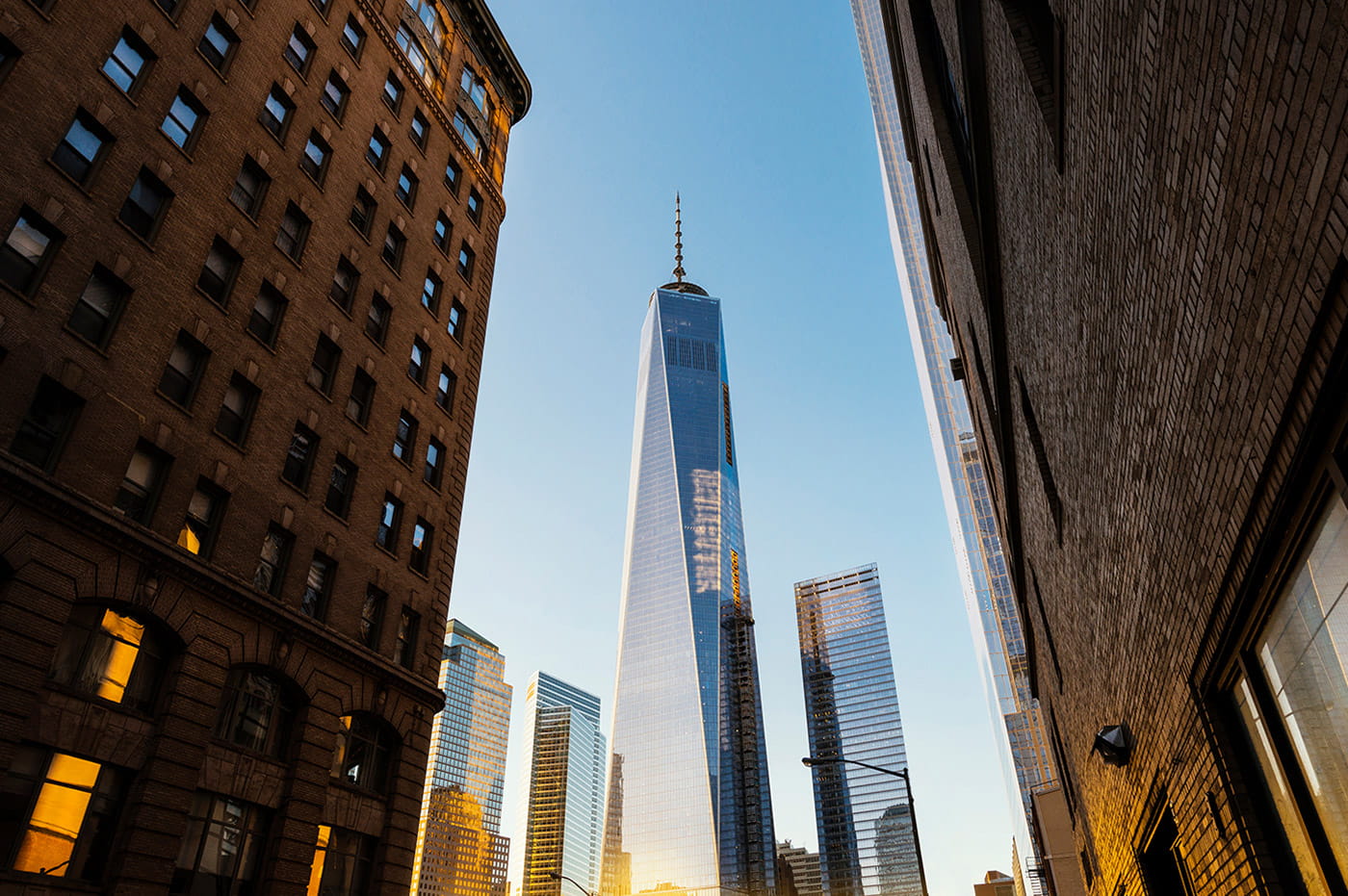 Large glass skyscraper in between two dark stone buildings.