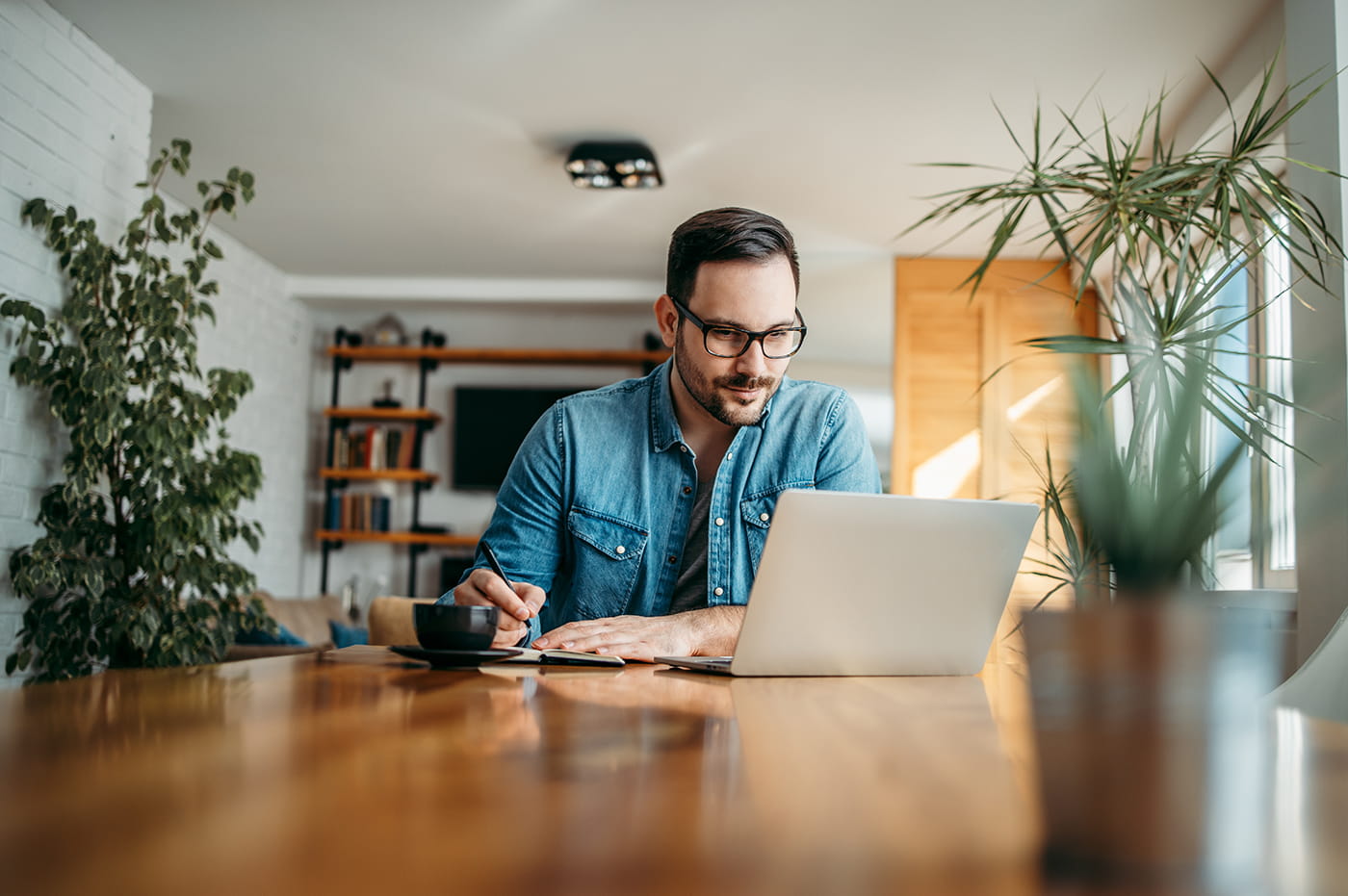 Man with glasses working on laptop.