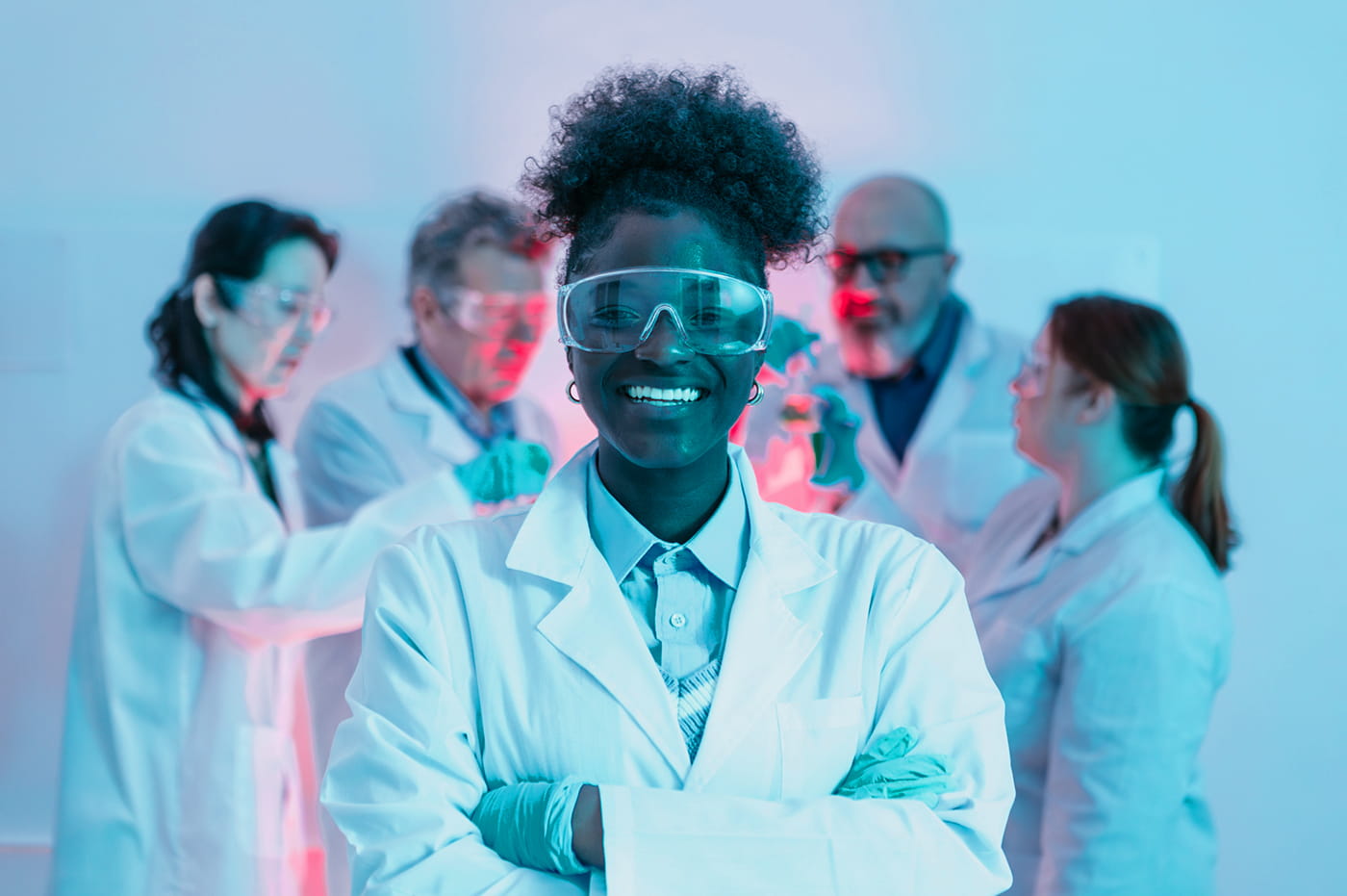 A Woman Scientist/Doctor Standing in front of a group of people smiling 