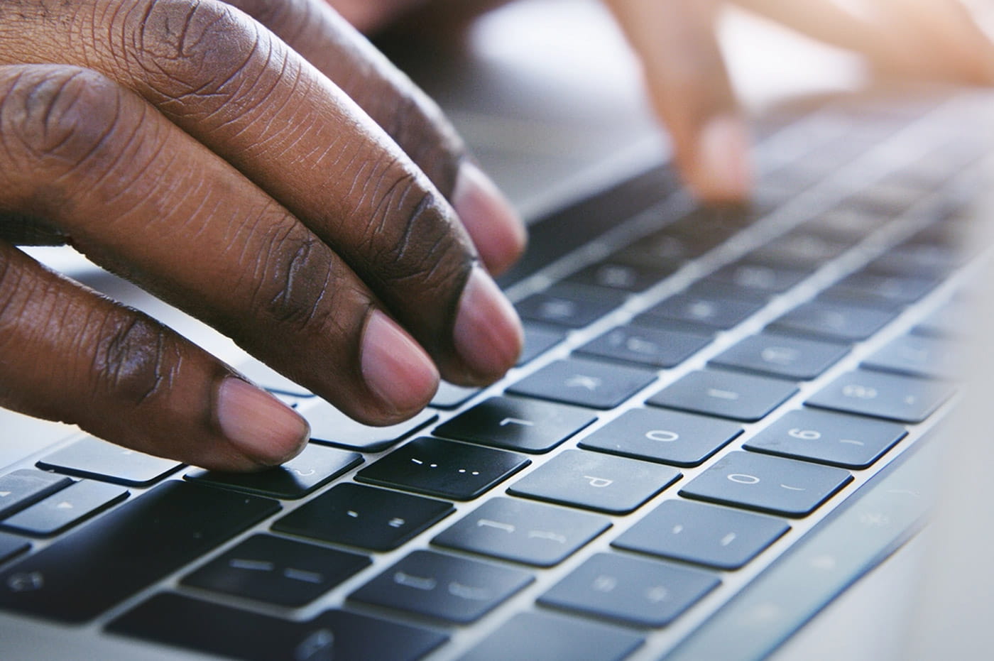 Closeup of person's hands typing on a laptop keyboard.