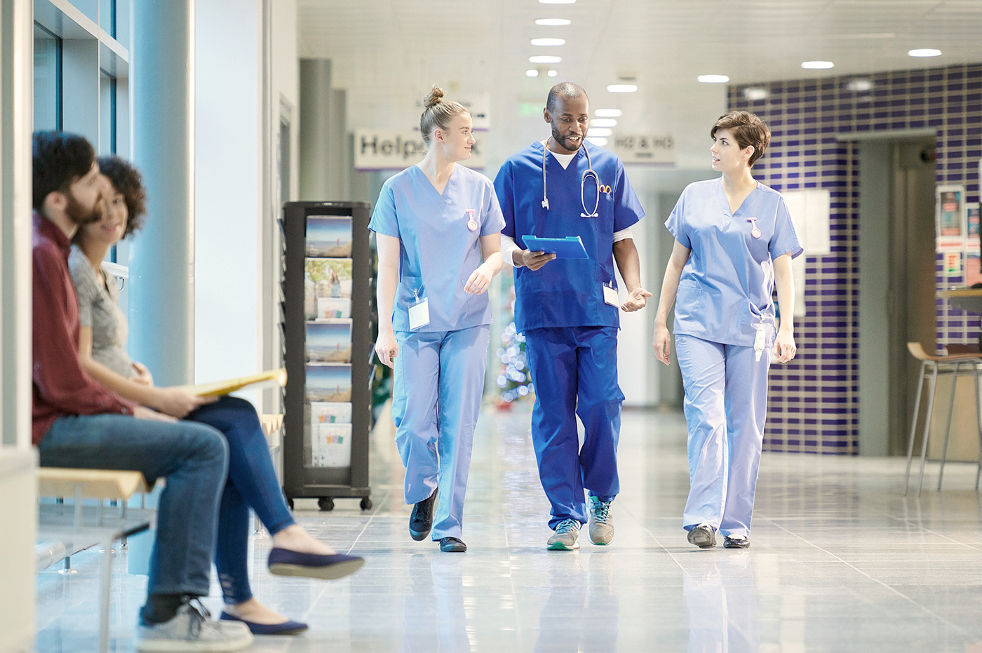Three healthcare workers walking in a hospital and discussing files.