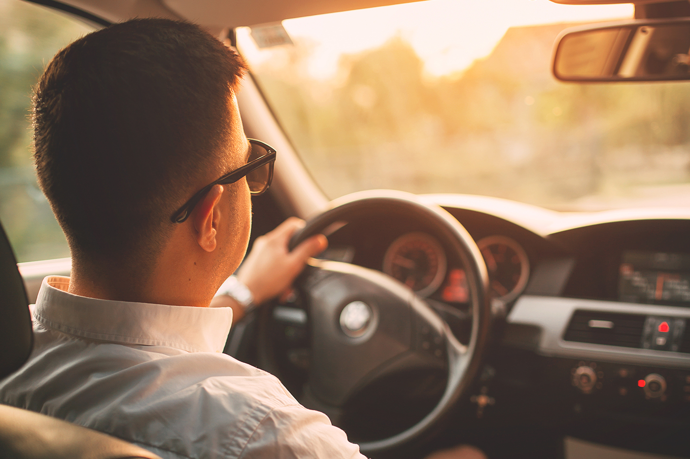 Man in car driving in the sunset.