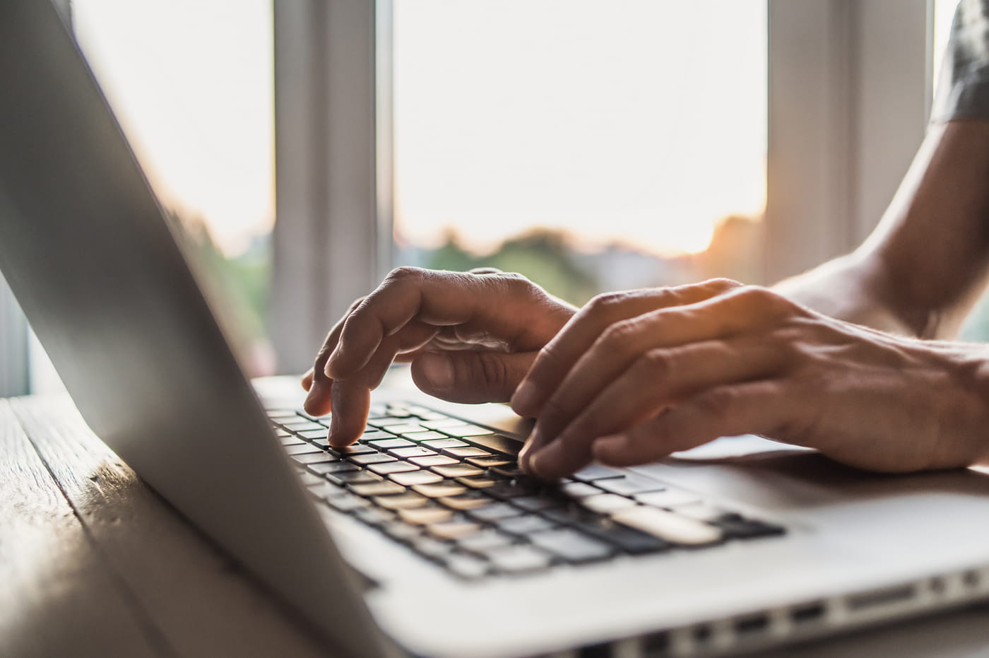 Hands typing on a laptop keyboard.