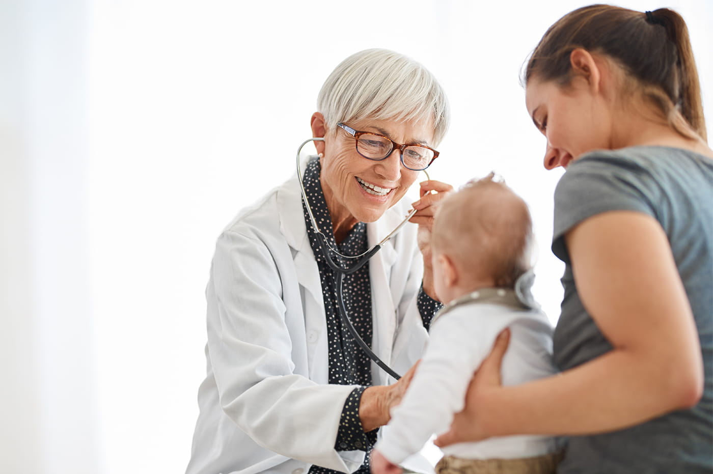 Older female doctor listening to a baby's heartbeat.