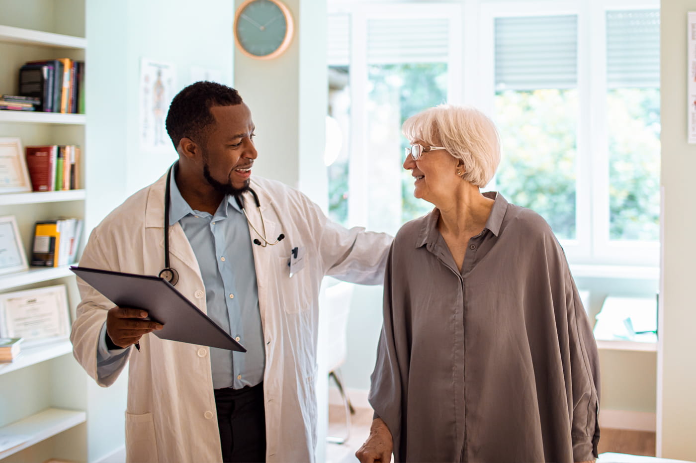 Male doctor talking with older female patient and smiling.