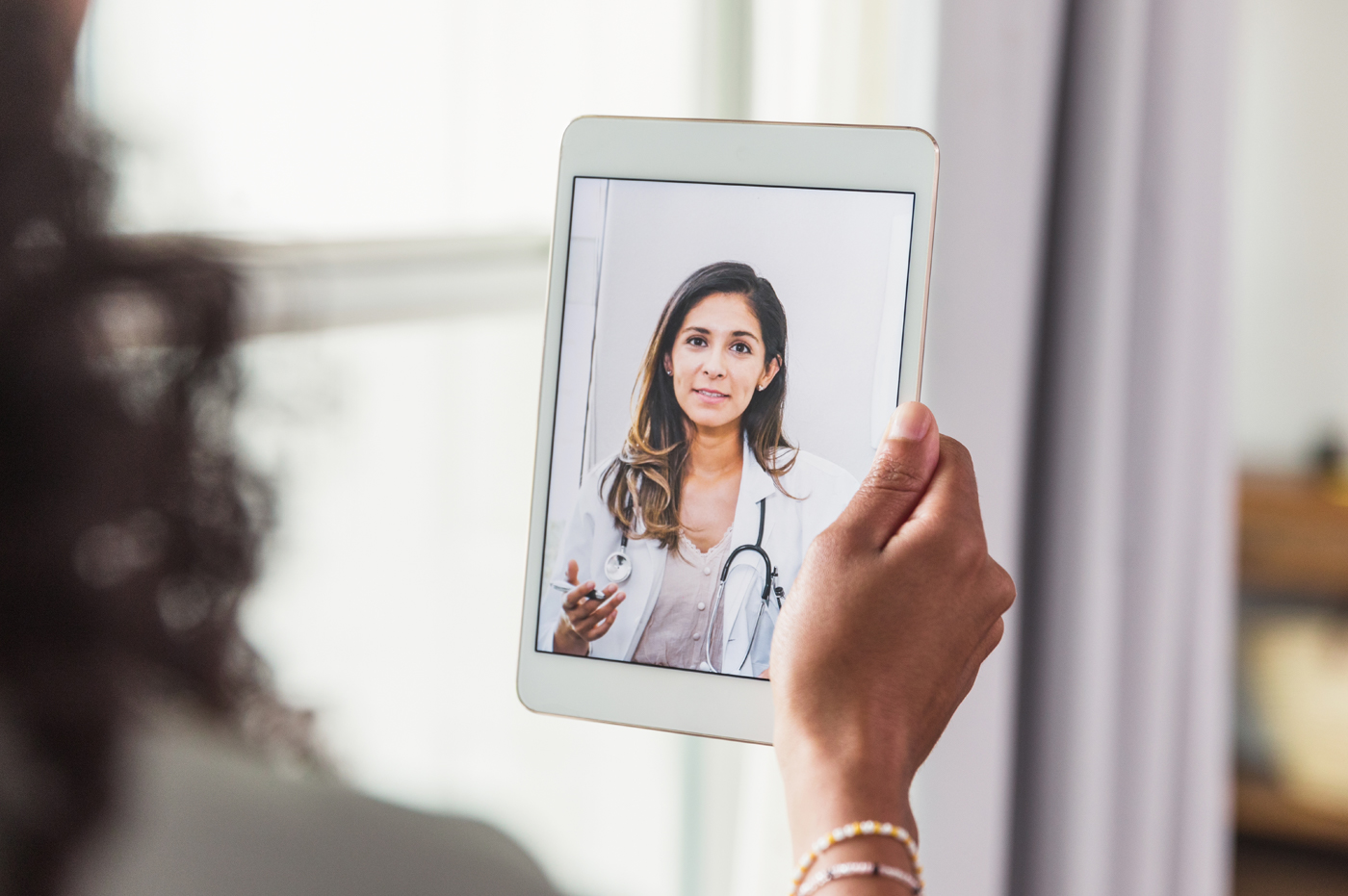 Female doctor on iPad screen during a virtual appointment.