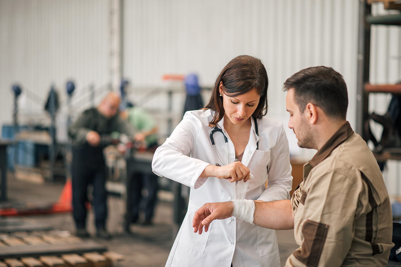 Female doctor wrapping a man's injurt with bandages.