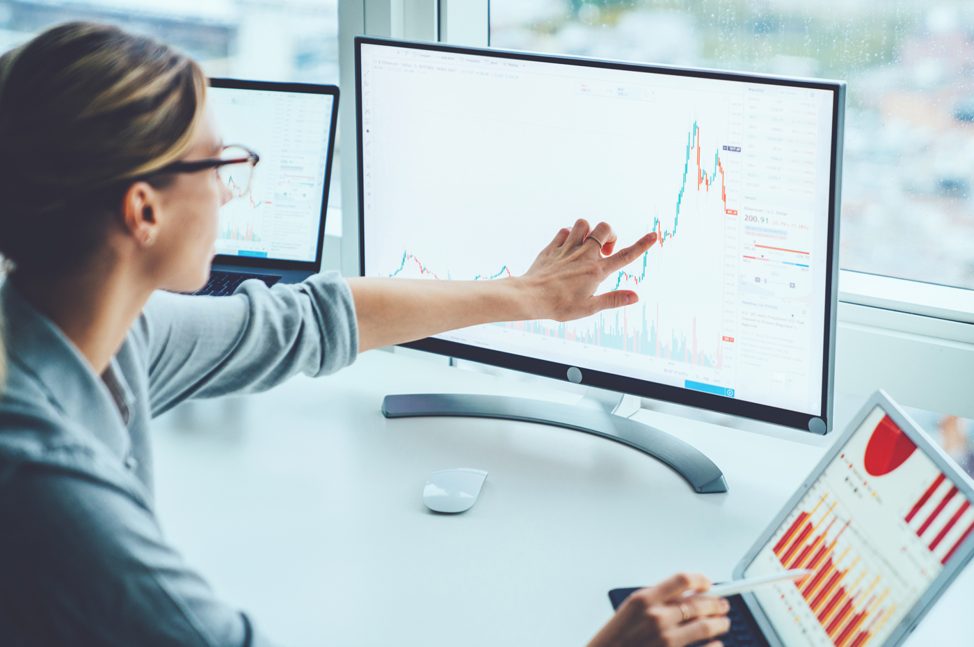 Business woman working with data charts on desktop and iPad.